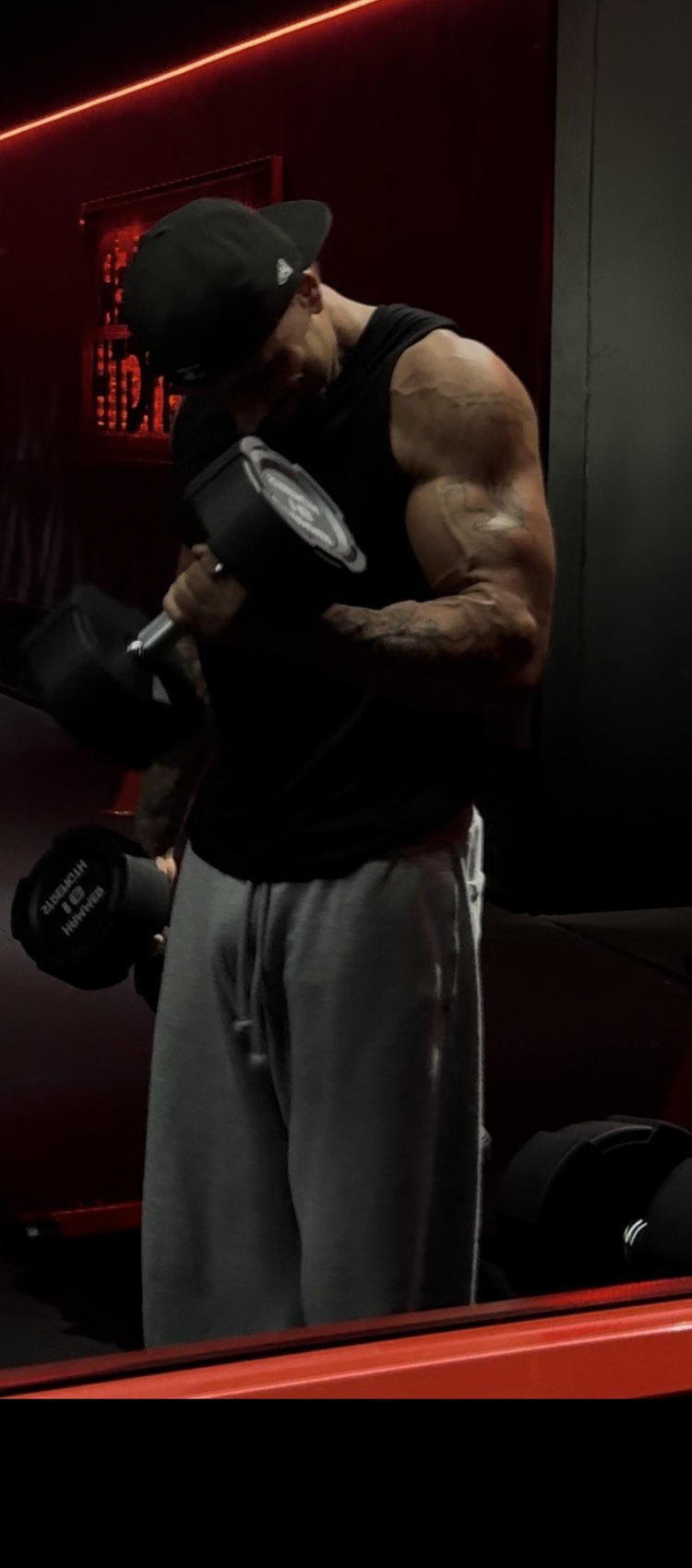 Enzo en plein curl biceps, concentré, dans la salle en pénombre
